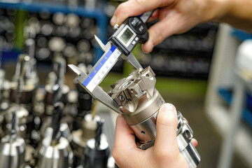 The worker measures the cutters with a caliper to work on milling and turning machines.