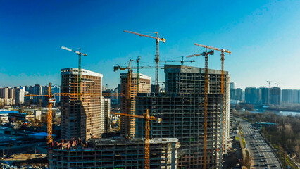 Crane and building construction site against blue sky. 