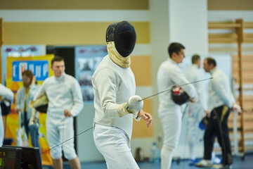 Athletes fencing in a suit uniform with a sword and mask, competition or warm-up. An active Olympic...