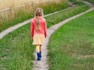 Dziewczynka w kaloszach na polnej drodze