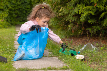 Girl collection plastic garbage in nature. kid picking up trash in park. Earth Day April 22. Save planet.  volunteer child cleaning forest environment from rubbish pollution. World Environment Day