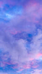 Cloudscape up view. Blue sky with pink and purple cumulus clouds in the evening at sunset. Vertical...