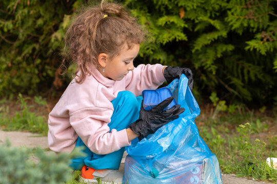 Girl collection plastic garbage in nature. kid picking up trash in park. Earth Day April 22. Save planet.  volunteer child cleaning forest environment from rubbish pollution. World Environment Day