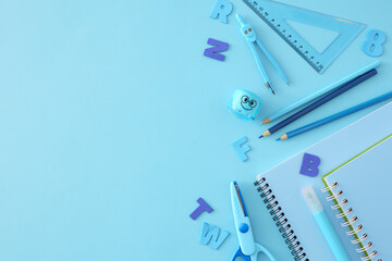 Core of learning idea. Top view composition of copybooks, marker, pencils, compass, sharpener, ruler, scissors, blue letters on light blue background with empty space for advert or text