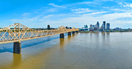 Panoramic aerial rose gold truss arch bridge over Ohio River leading to downtown Louisville KY