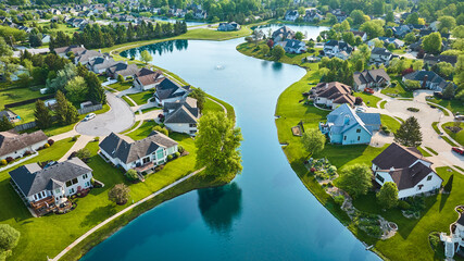 Split neighborhood with large winding pond with fountain and cul-de-sac housing additions aerial