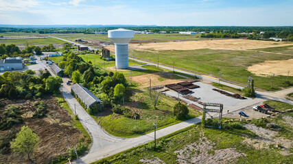 Railroad parts yard tracks and metal beams, non-descript water tower middle of nowhere farmland
