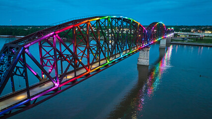 Arch bridge aerial rainbow pride illuminated at night with reflected colors in water over Ohio River