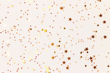 Glowing gold colored stars and crystals confetti on a gray background. Festive concept. Selective focus.