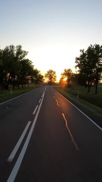 On a rural road to sunset, vertical pov