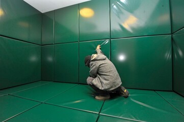 Man kneeling in green padded cell - obrazy, fototapety, plakaty