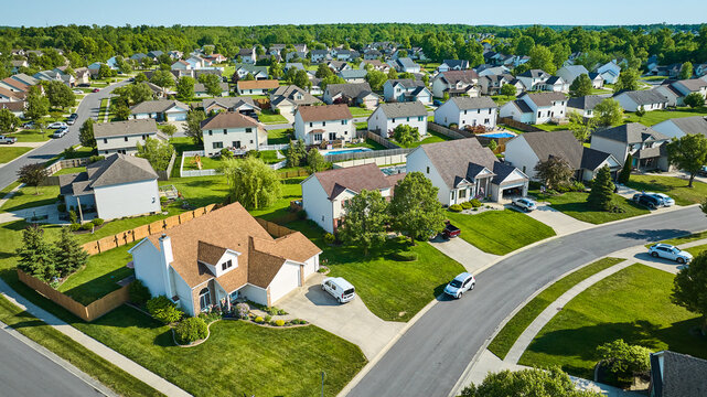 Two story houses in neighborhood aerial with cars in driveways and the street