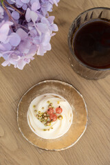 Sweet dessert with cream and coffee on wooden cafe table with flowers top view, flat lay