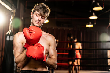 Boxing fighter shirtless posing, caucasian man boxer wearing red glove in defensive guard stance ready to fight and punch at gym with ring and boxing equipment in background. Impetus - Powered by Adobe