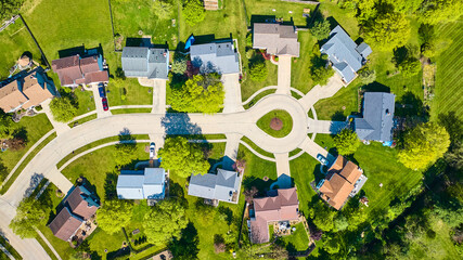 Downward rooftop view of eight suburban neighborhood homes of varying colors aerial