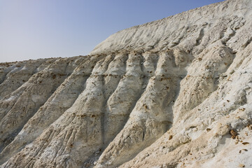 Fototapeta na wymiar The slope of Mount Bokty from limestone and chalk deposits in the Kazakh steppe, the relief of the hillside, ditches and gullies washed out by water