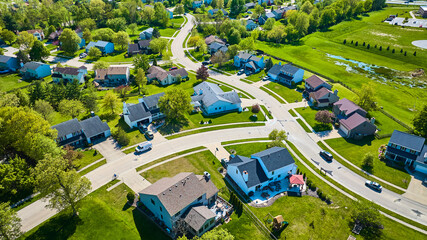 Snaking roads through small neighborhood with water runoff nearby in aerial