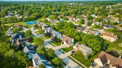 Neighborhood with amenities middleclass housing addition in summer with tennis court aerial