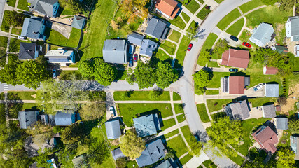 Downward neighborhood shot of houses in summer with green lawn and trees aerial