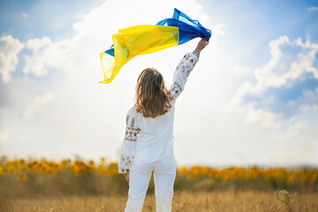 Happy ukrainian woman with national flag on summer sky background.