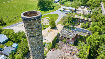 Rural abandoned building, decaying, old, crumbling, collapsed roof, tall silo smokestack aerial