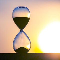 Hourglass on the background of a sunset. The value of time in life. An eternity.