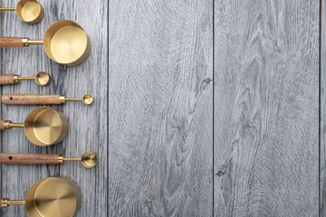 Copper measuring cups with wooden handles on gray kitchen table. View from above. Space for text.