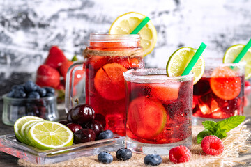 Refreshing berry cocktail with ice and lemon. Raspberry, lime, strawberry, blueberry, and leaves...