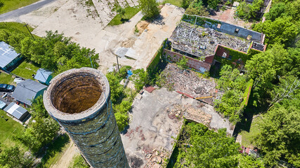 Aerial smokestack silo brick at old abandoned farm building with green ivy growing up walls