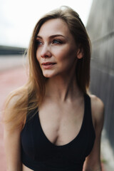 Portrait of a beautiful girl with long hair dressed in black sportswear who looks into the distance and mentally tunes in to the upcoming morning workout. - 626693613