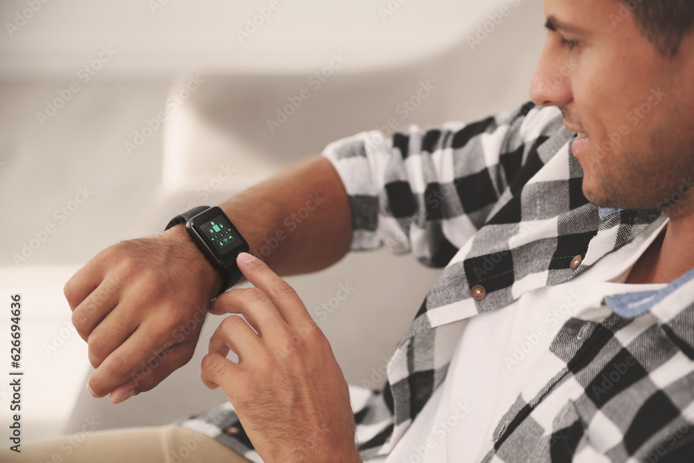 Poster man setting smart home control system via smartwatch indoors. app interface with icons on display