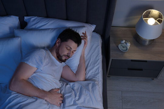 Man sleeping in bed at night, above view