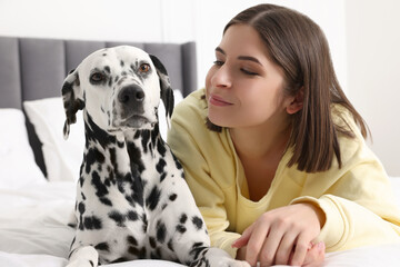 Beautiful woman with her adorable Dalmatian dog on bed at home. Lovely pet