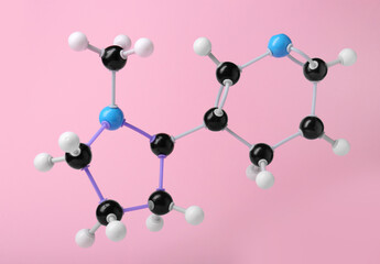 Molecule of nicotine on pink background. Chemical model