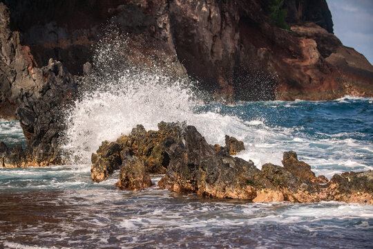 Sea collides with the stones and sand of a beach. Sea waves lash line impact rock.