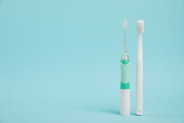 Electric and plastic toothbrushes on light blue background, space for text