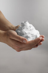 Man holding shaving foam on light grey background, closeup