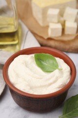 Delicious tofu sauce and basil leaves on white table, closeup