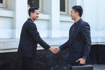 Two business colleagues shaking hands outdoors. Handshake between two businessmen. Greeting, dealing, merger and acquisition concepts