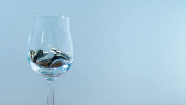 Coins fill glass goblet in stop motion