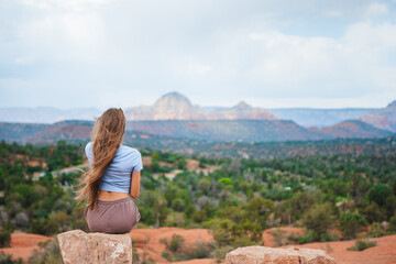 Girl enjoys the view of the Sedona landscape from the top of the Bell Rock hiking trail, famous for its many energy vortexes and red rocks.