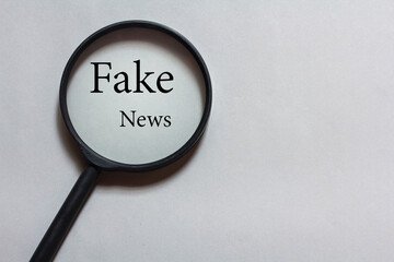 magnifying glass on gray background. magnifying glass with fake news text