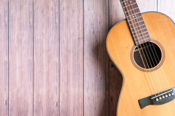 Naklejka premium Acoustic guitar resting on rustic wooden background. Copy space.