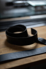 Man doing leatherwork, in a leather working workshop, making a black leather belt
