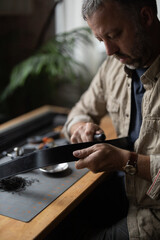Man doing leatherwork, in a leather working workshop, making a black leather belt