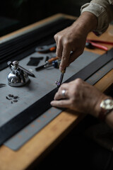 Man doing leatherwork, in a leather working workshop, making a black leather belt