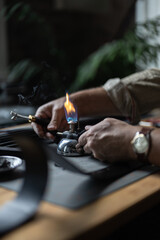 Fototapeta na wymiar Man doing leatherwork, in a leather working workshop, making a black leather belt