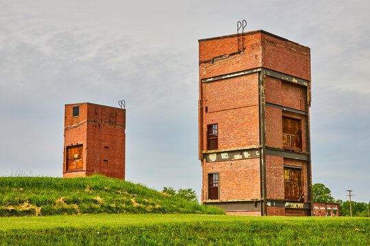 Decaying Old Buildings On Grassy Hill Under Gray Sky That Used To Be Old Freight Elevators