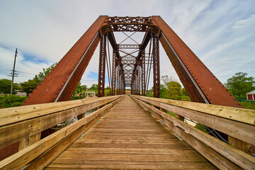 Fototapeta na wymiar Wooden walking bridge cutting through rusty iron train bridge in Mount Vernon Ohio