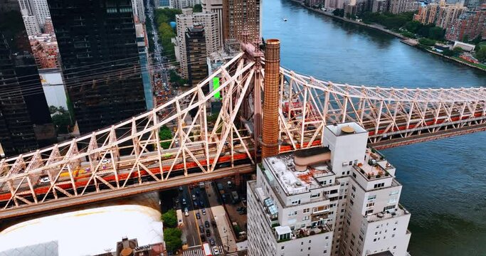 Support of the Queensboro Bridge above Hudson River. Multiple cars drive by the roads of New York below the bridge. Top view.